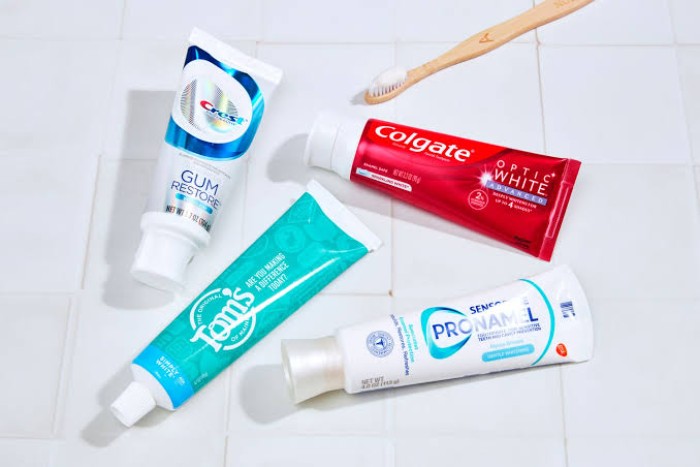 A selection of top toothpaste brands displayed beside a toothbrush on a flat surface