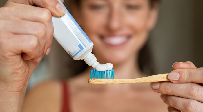 A woman using proper toothpaste and a toothbrush for post-dental treatment care